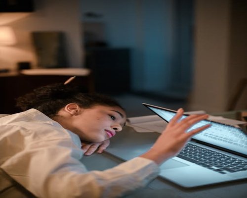 Exhausted Indonesian worker at laptop late in the day